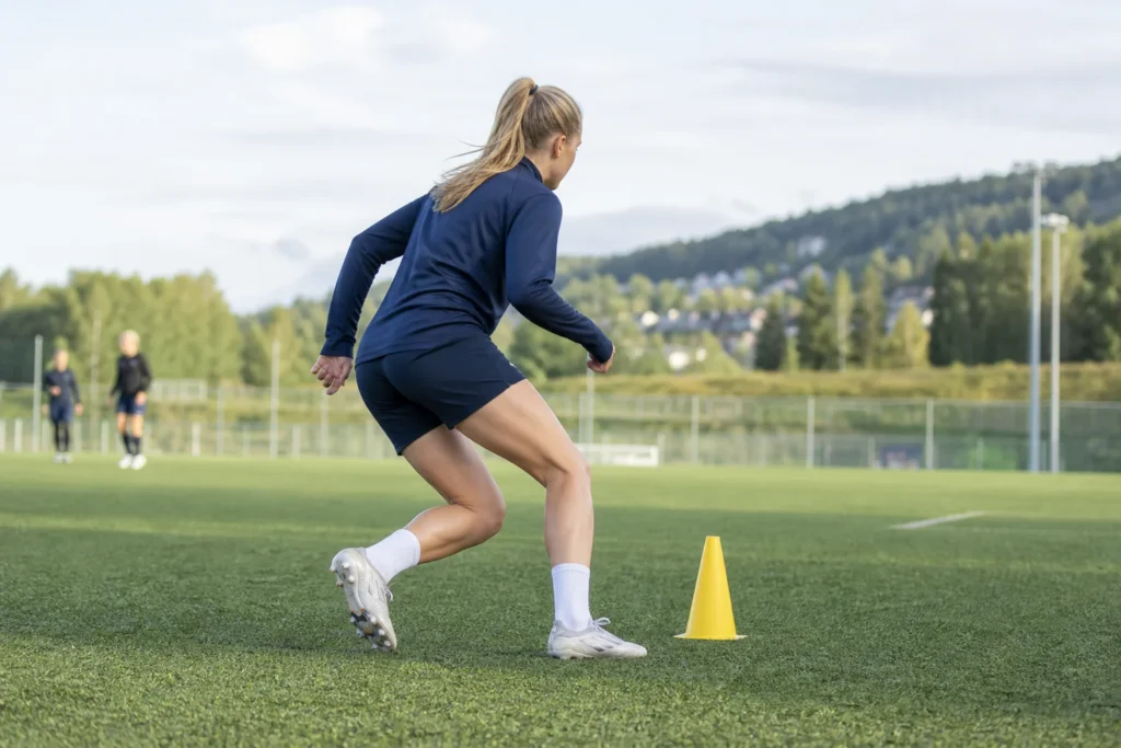 Fotballspiller skifter retning rundt en kjegle